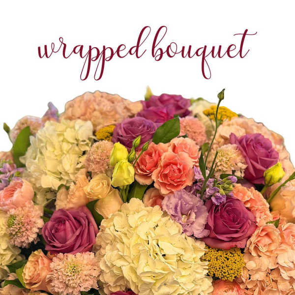 Wrapped bouquet of pink and peach blooms with purple roses and ivory hydrangeas