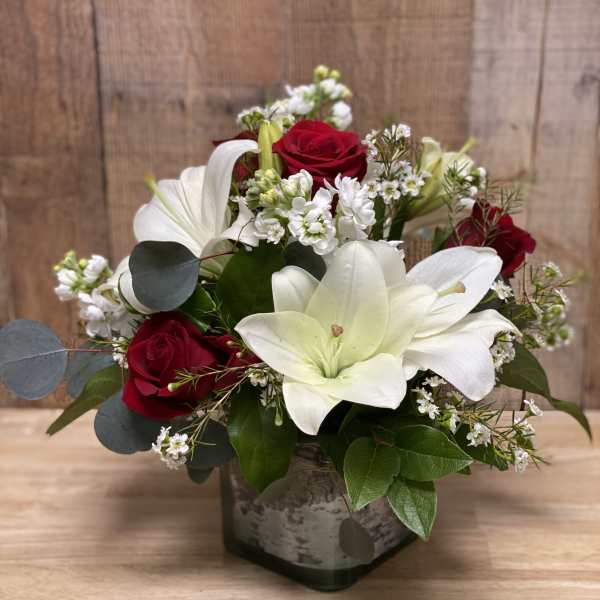 Red roses and white lilies arranged in a square vase