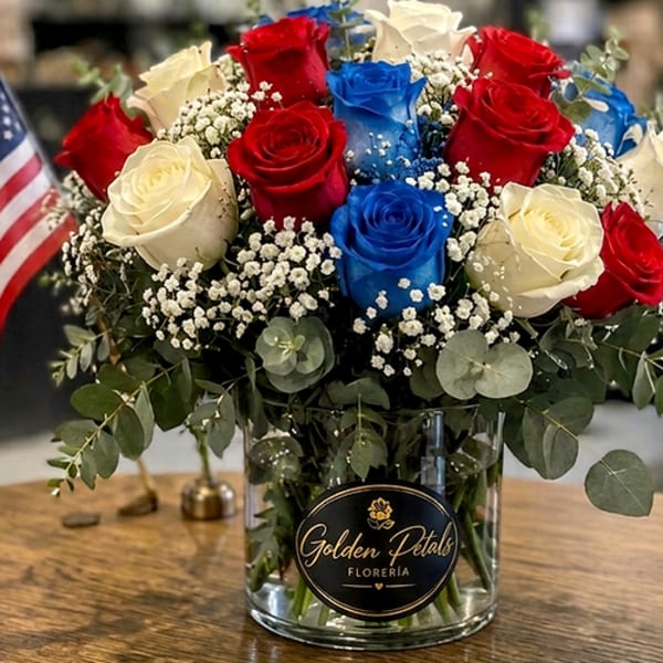 Red, white, and blue roses in a glass vase with baby's breath