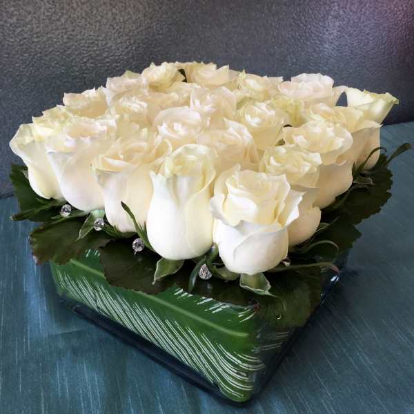 White rose arrangement in a green square vase