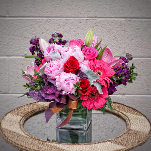 Pink and purple bouquet in a square glass vase with ribbon