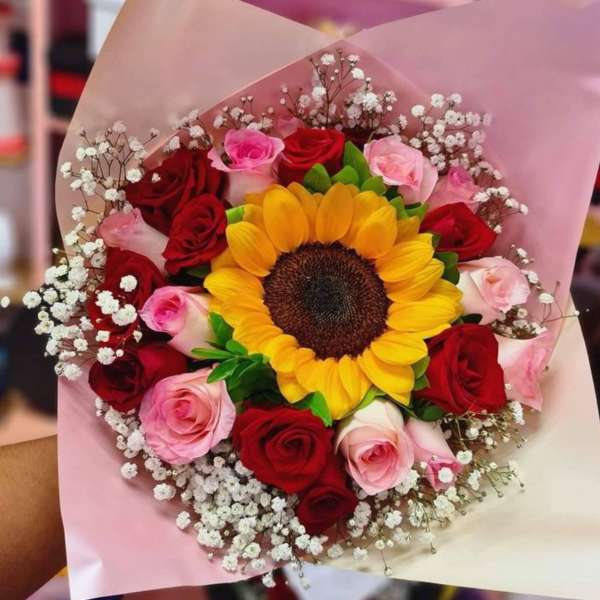 Bouquet of red and pink roses with a sunflower center