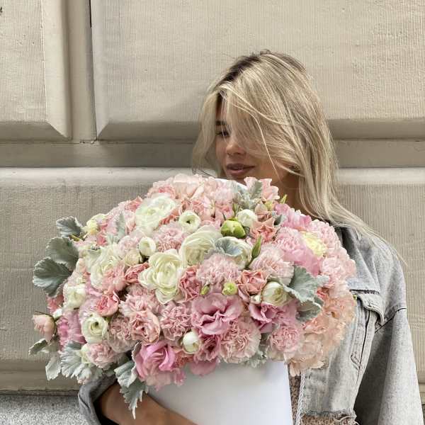 Woman holding a large pastel pink and white bouquet in a white box