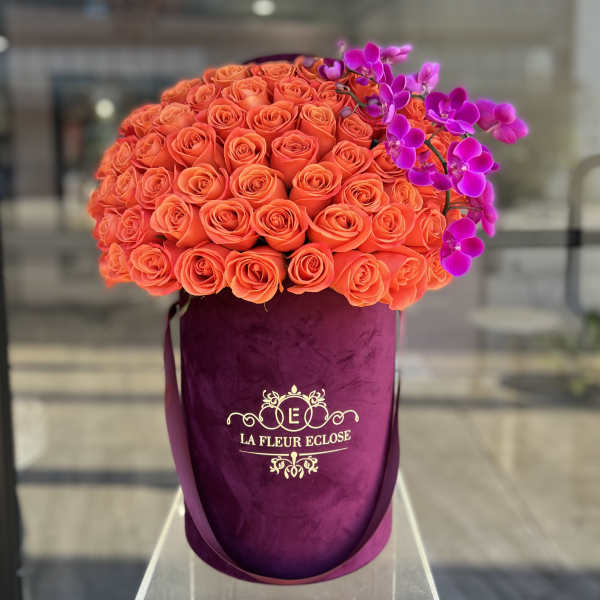 Orange rose bouquet with purple orchids in a velvet hatbox