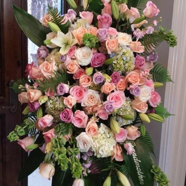 Large pastel rose and lily standing spray on an easel