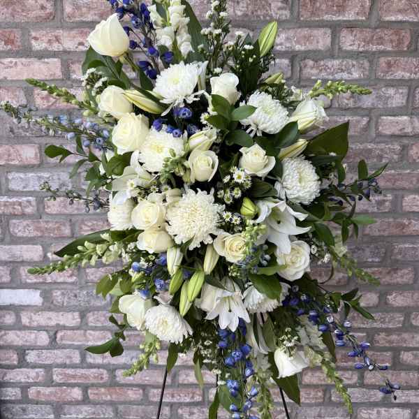 Large white and blue floral standing arrangement on a black easel