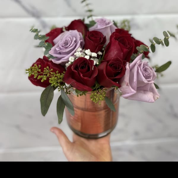 Red and lavender roses arranged in a copper vase