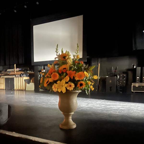 Orange and yellow floral arrangement in a pedestal vase