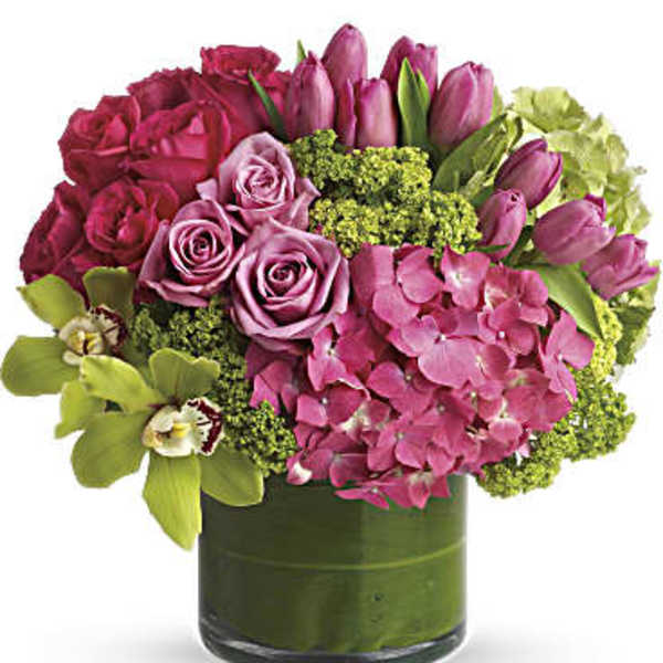 Pink roses, tulips, and hydrangea in a green glass vase