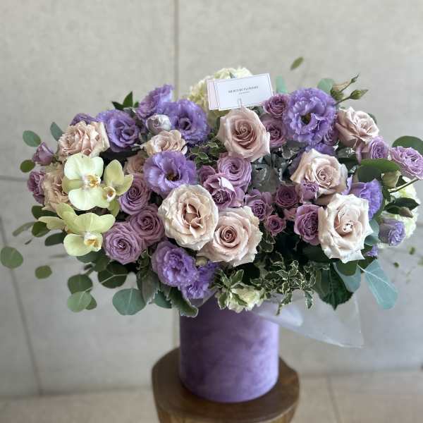 Lavender and blush bouquet with roses and orchids in a purple box