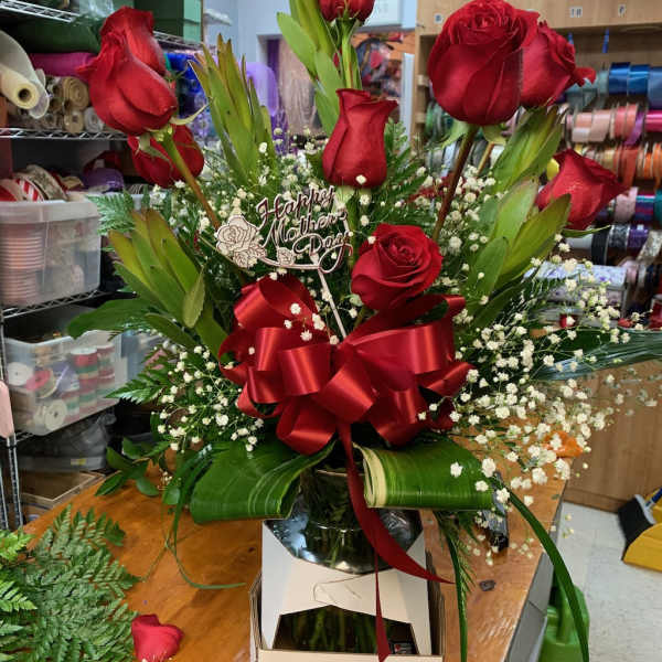 Red roses arranged with baby's breath and a red ribbon in a box.