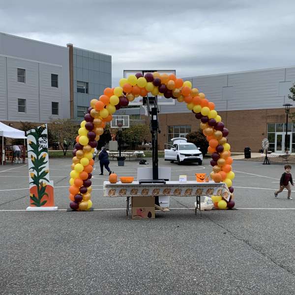Balloon arch in yellow, orange, and burgundy at an outdoor event