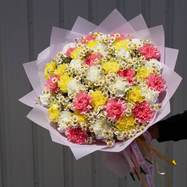 Large bouquet of pink, yellow, and white carnations with tiny daisies