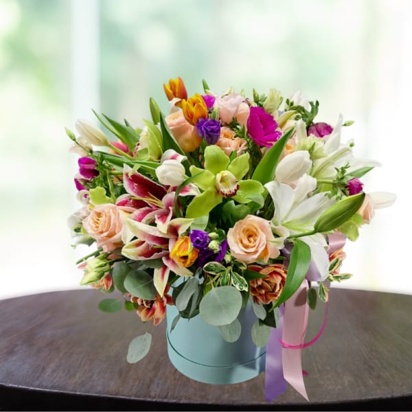 Mixed bouquet of lilies, roses, and orchids in a blue hatbox