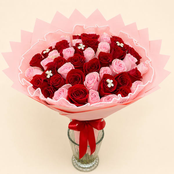 Bouquet of red and pink roses in pink wrapping with a glass vase