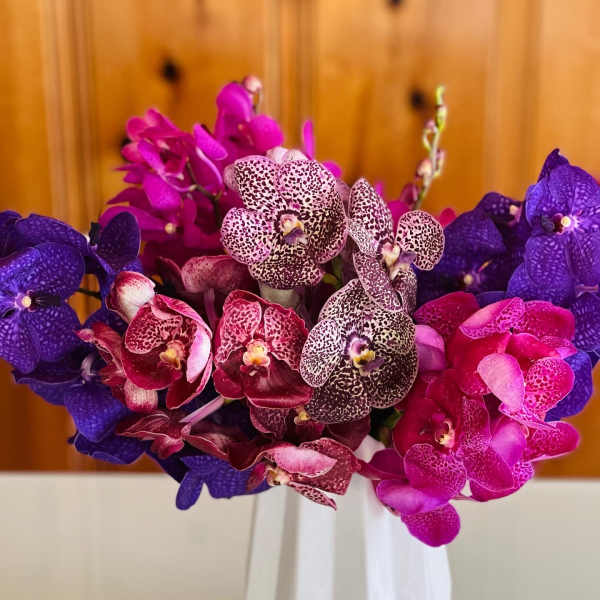 Bouquet of purple and pink orchids in a white vase