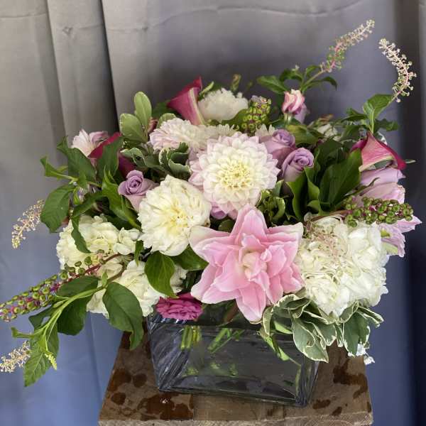 Pink and white floral arrangement in a square glass vase
