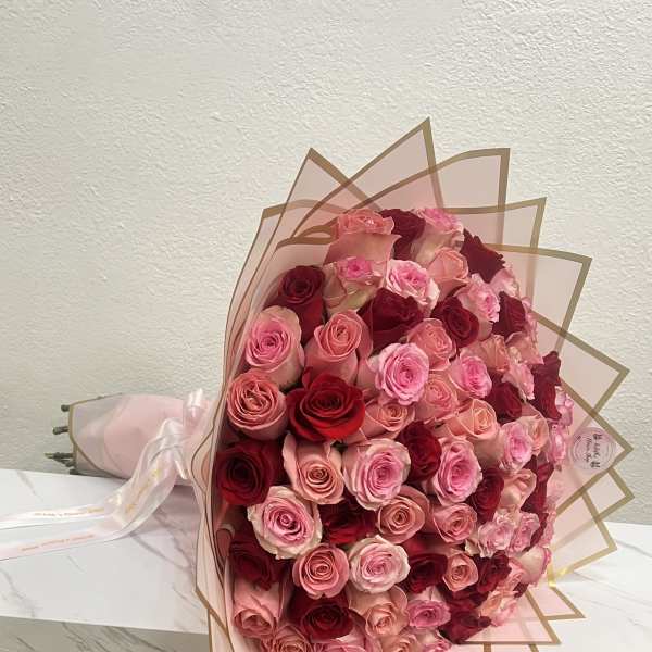 Large bouquet of pink and red roses wrapped in blush paper