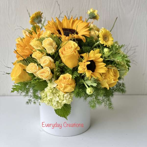 Yellow roses and sunflowers arranged in a white vase