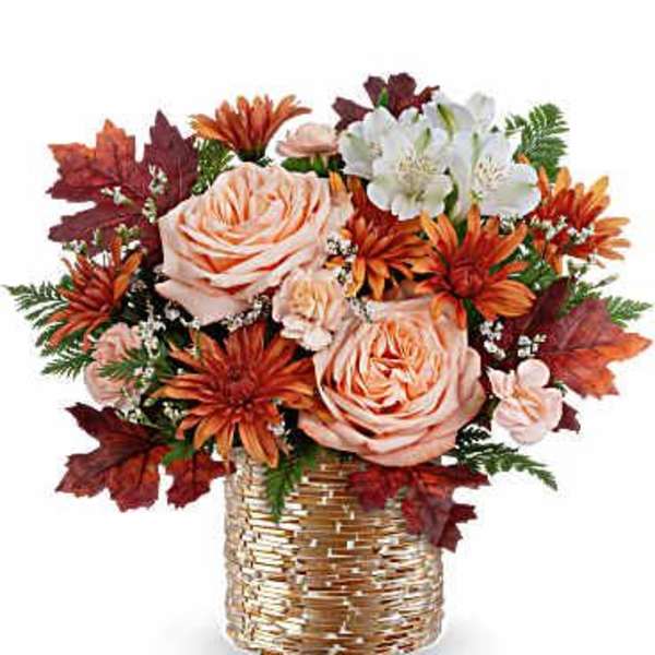 Autumn bouquet of peach roses and orange flowers in a gold basket vase