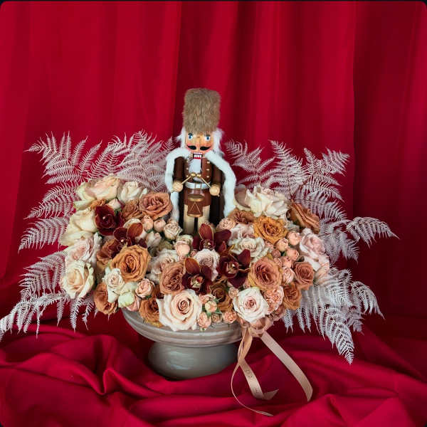 Rose arrangement with a nutcracker figurine in a gray pedestal bowl