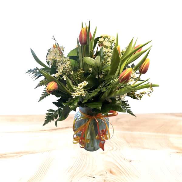 Bouquet of orange tulips and white filler flowers in a glass vase