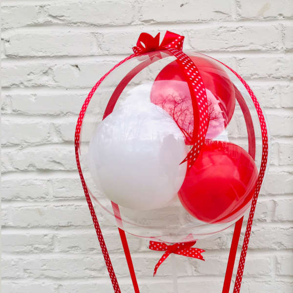 Red and white balloon arrangement with a small flower basket at the base