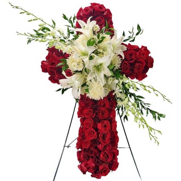 Cross-shaped floral tribute with red roses and white lilies on a stand