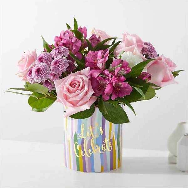 Pink roses and purple flowers in a striped "Let's Celebrate" vase