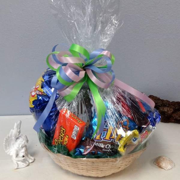 Basket of assorted candies wrapped in clear cellophane with a pastel ribbon bow