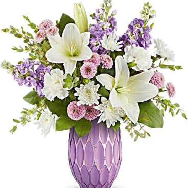 White lilies and purple flowers arranged in a lavender vase