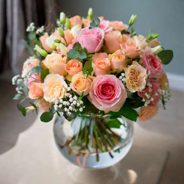 Bouquet of pink and peach roses in a clear glass vase