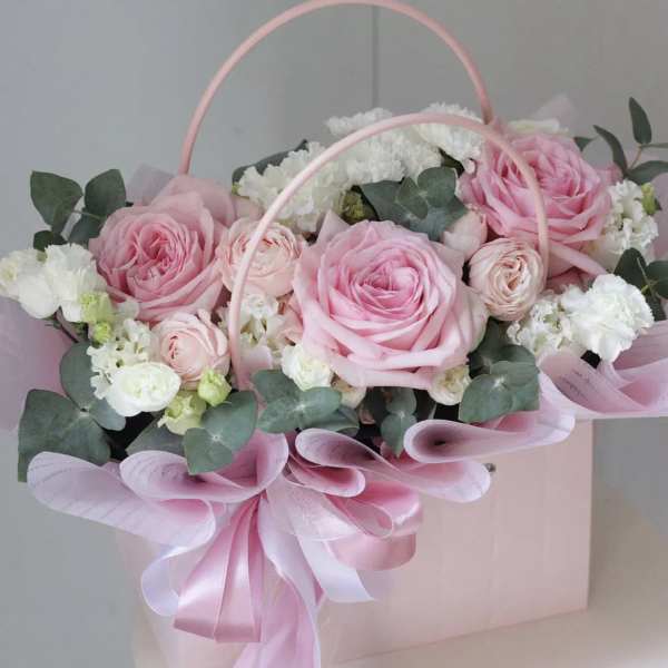 Pink roses and white flowers in a pale pink gift box with ribbon