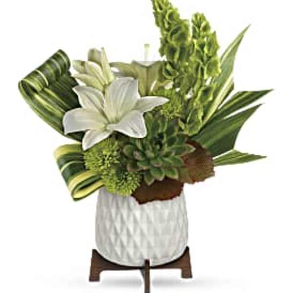 Compact white and green arrangement with lilies, succulents, and tall blooms in a white pot on a wooden stand
