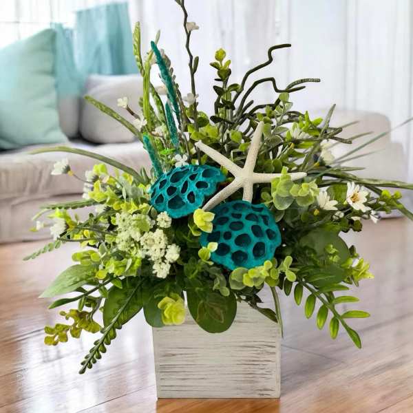 Tropical floral arrangement in a white square vase with starfish accents
