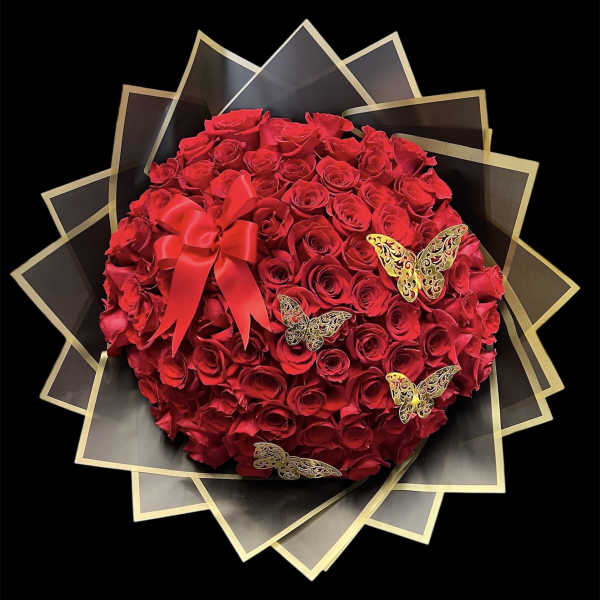 Round bouquet of red roses with a red ribbon and butterfly accents
