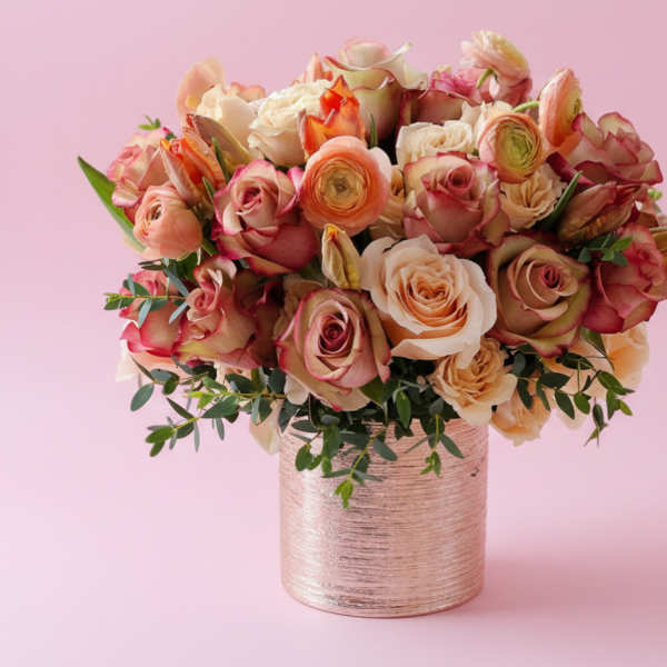 Pink and peach roses arranged in a metallic vase