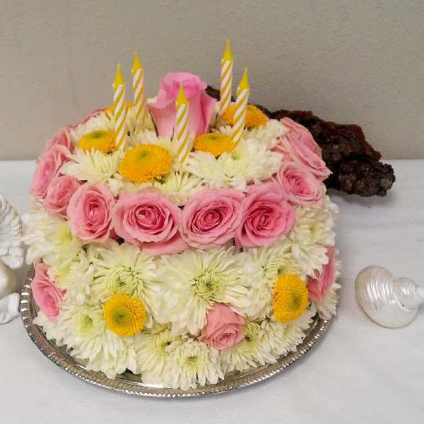 Pink roses and white daisies arranged as a cake with candles