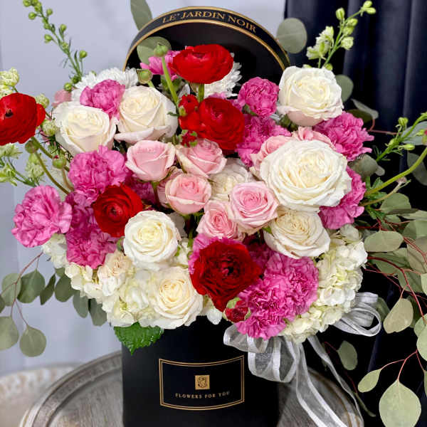 Round box arrangement of red, pink, and white roses with carnations