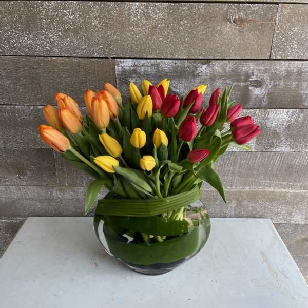 Colorful tulips arranged in a round glass vase