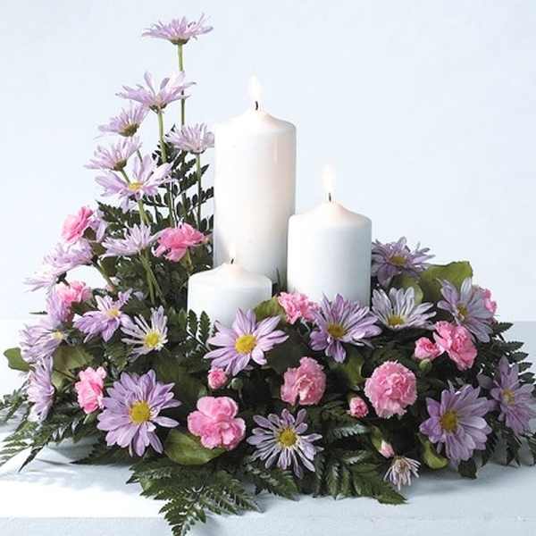 Floral arrangement with white candles and pink and lavender flowers