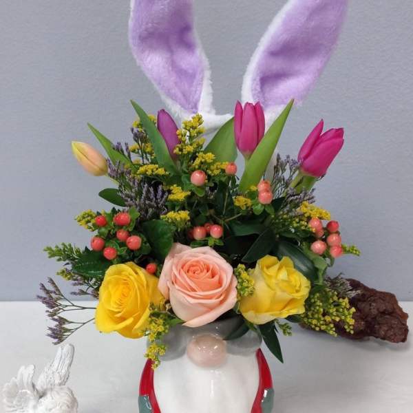 Floral arrangement in a bunny-shaped vase with tulips, roses, and bunny ears