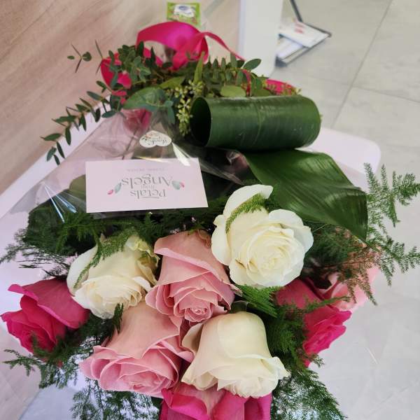 Hand-tied bouquet of pink and white roses with decorative greenery in clear wrap and a pink ribbon