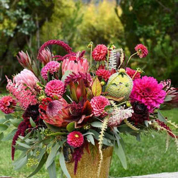 Bright pink and burgundy floral arrangement in a gold vase