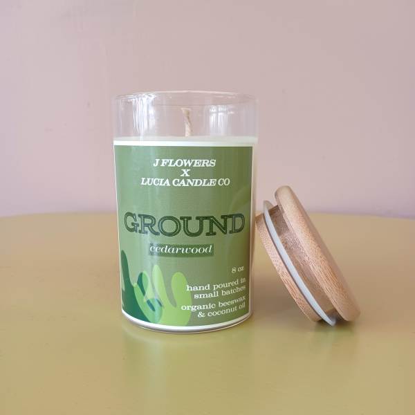 Green cedarwood candle in a glass jar with a wooden lid