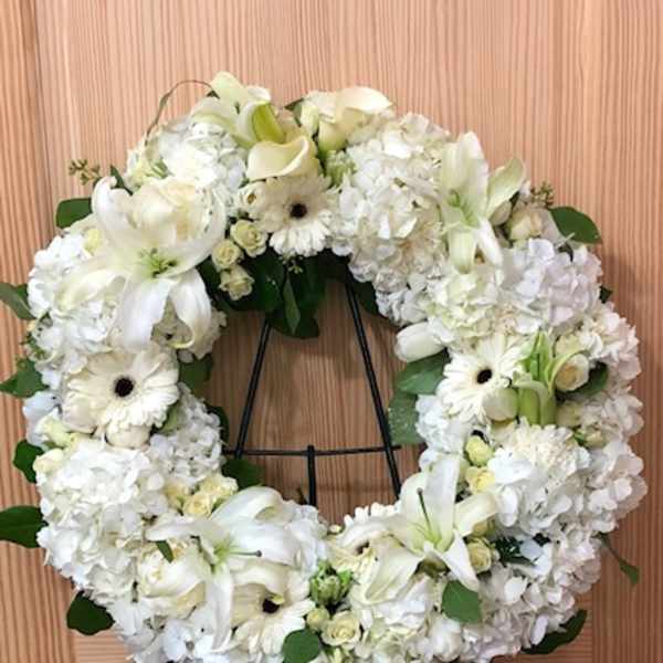 White floral wreath on a black stand