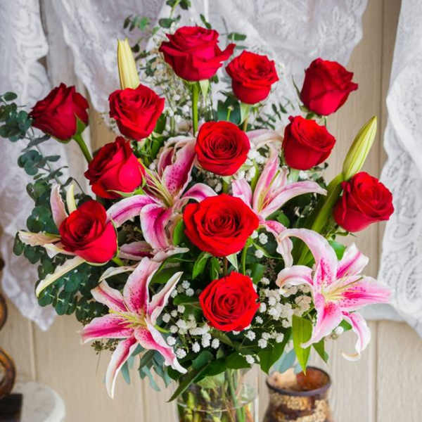Bouquet of red roses and pink lilies in a clear glass vase