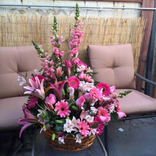 Pink mixed flower arrangement in a wicker basket