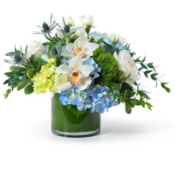 Low glass vase arrangement with blue hydrangeas, white roses, orchids, and green accents