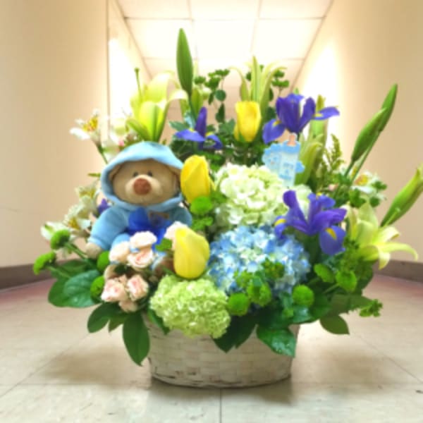 Basket arrangement with a teddy bear, lilies, tulips, and hydrangeas